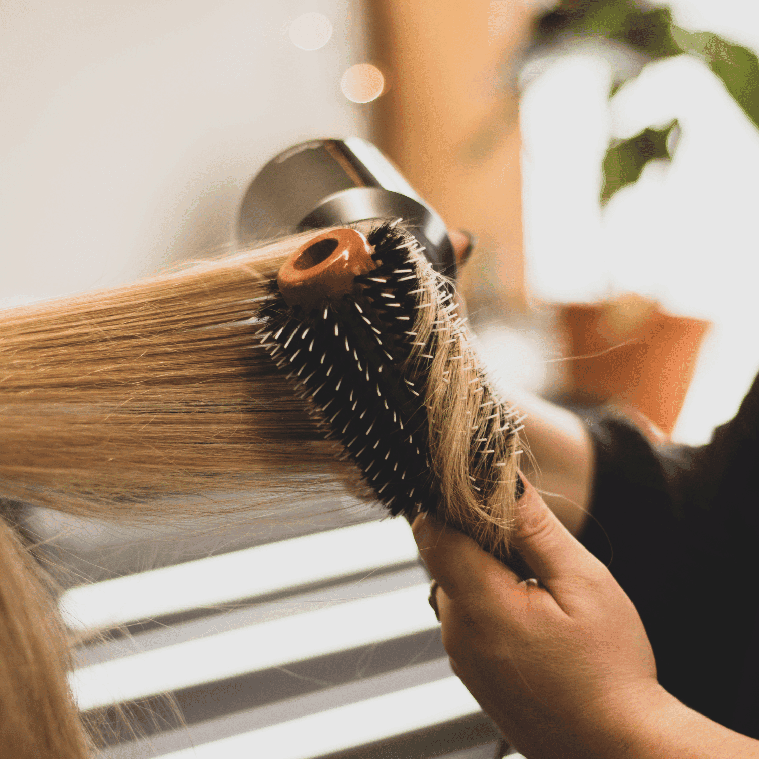 Hair being styled with a round brush and blow dryer in a salon setting.