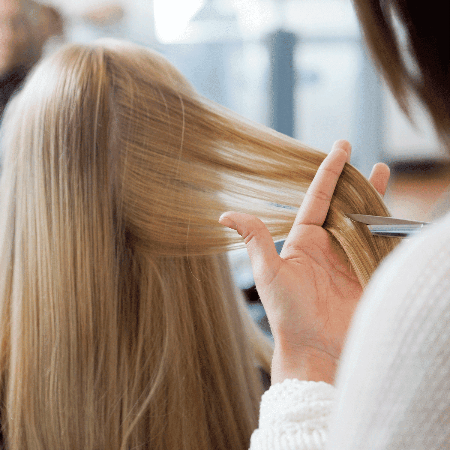 Hairdresser cutting long blonde hair in a salon.
